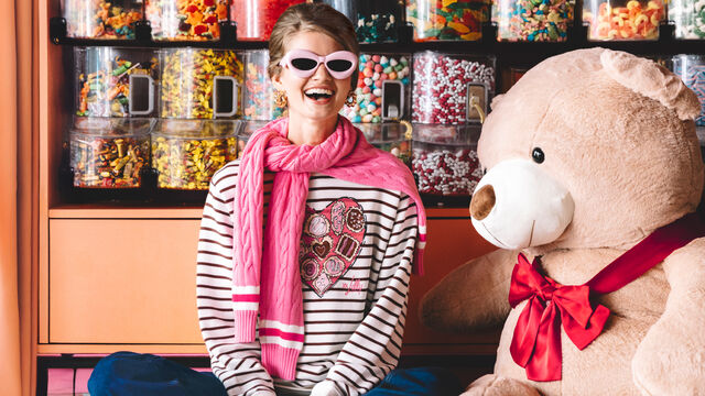 Model in novelty Valentine's Day sweatshirt sitting inside candy shop